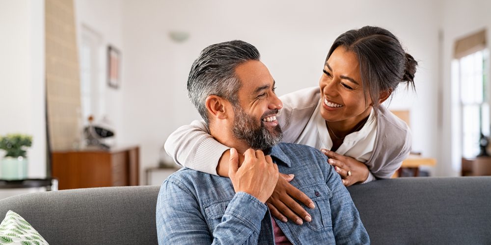 Smiling,Ethnic,Woman,Hugging,Her,Husband,On,The,Couch,From Dental Implants Near Me. brentwood dental veneers Dr. Kevin Ackerman Dr. Eric Towson Ackerman & Towson Dentistry. General, Cosmetic, Restorative, Preventative, Pediatric, Family Dentist in Brentwood CA 94513