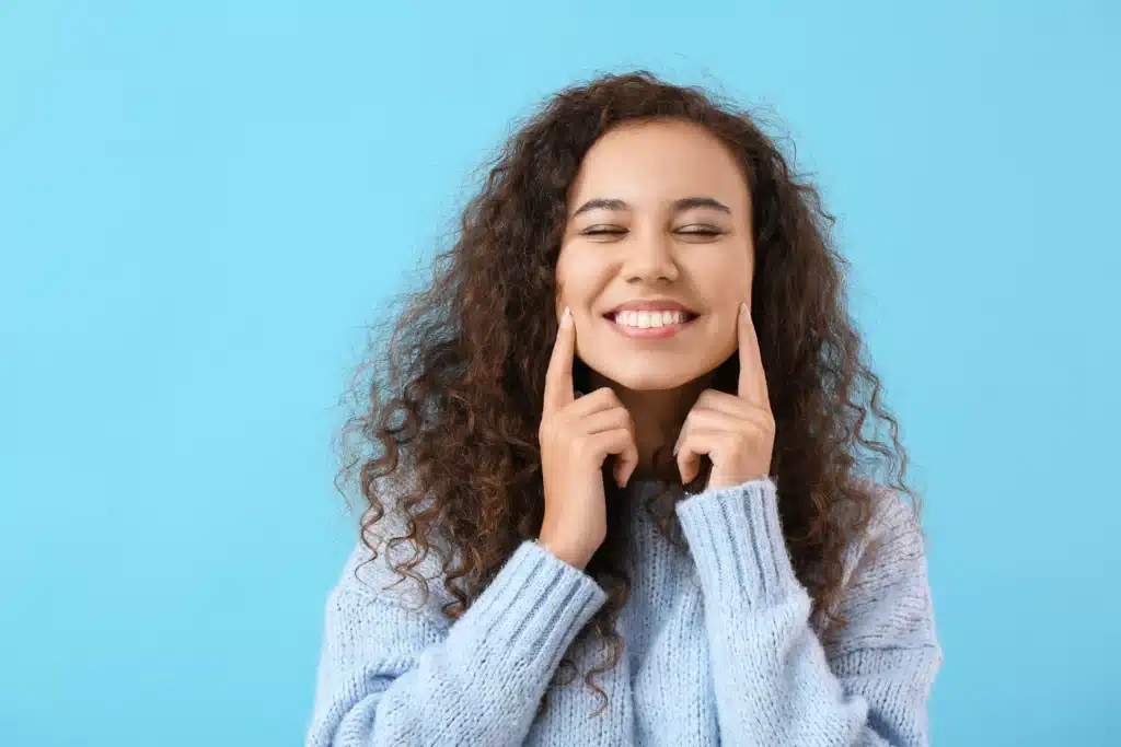 Curly-haired woman showing straight healthy smile after cosmetic dental treatment in Brentwood