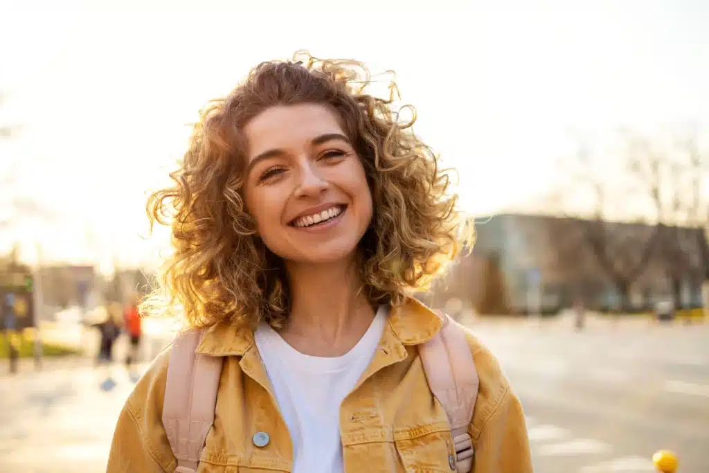Young woman with curly hair smiling after personalized dental care at Ackerman & Towson Dentistry