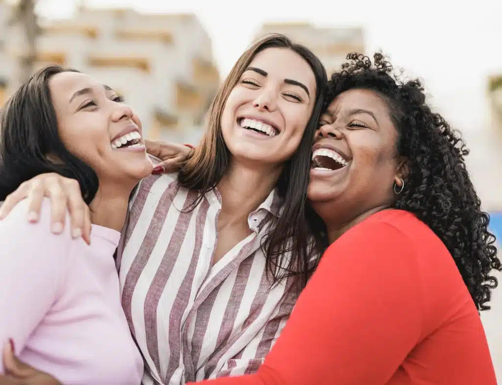 Women laughing together with bright smiles after cosmetic dentistry treatment